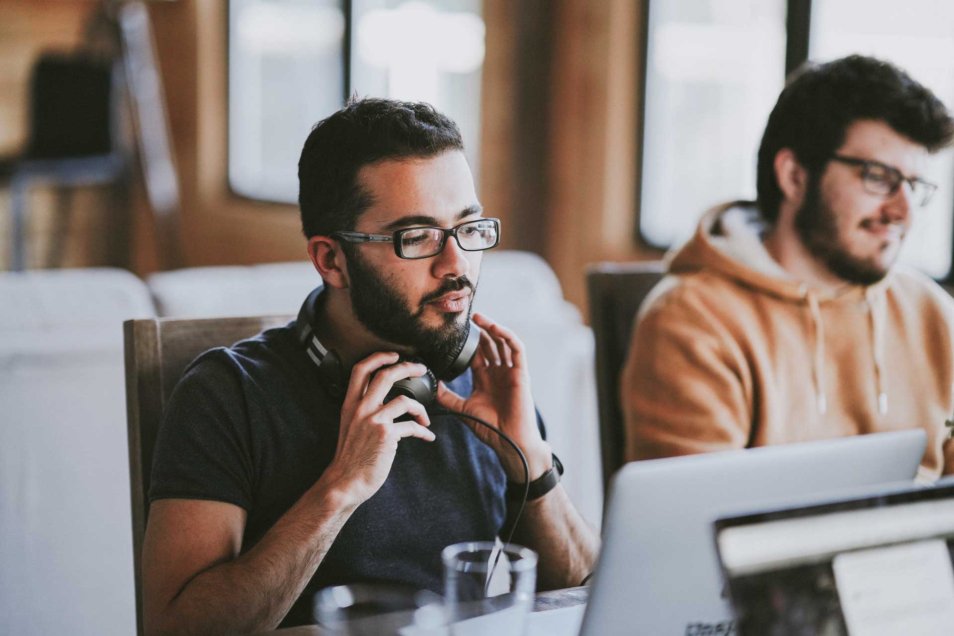 Two men with glasses sat working at computers