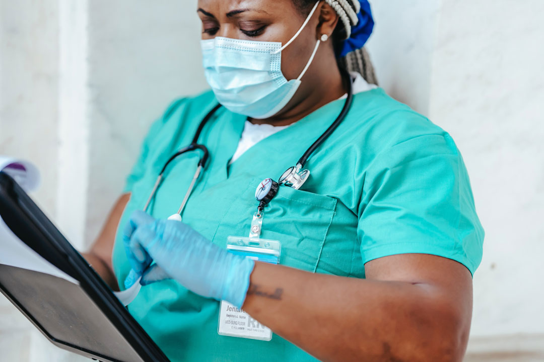 Nurse looking at clipboard with a face mask and gloves on