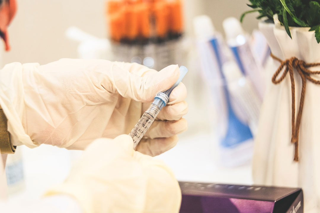 Two gloved hands holding a syringe