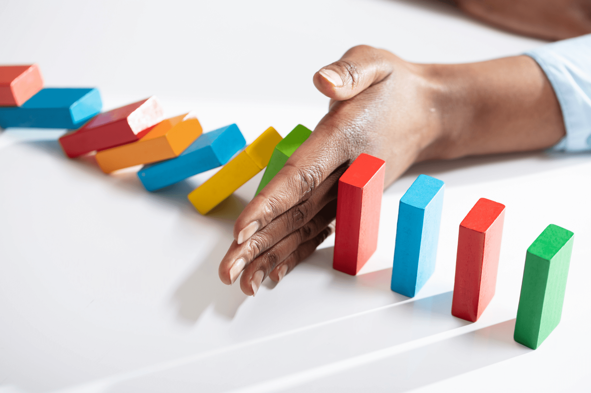 hand stopping dominoes from falling