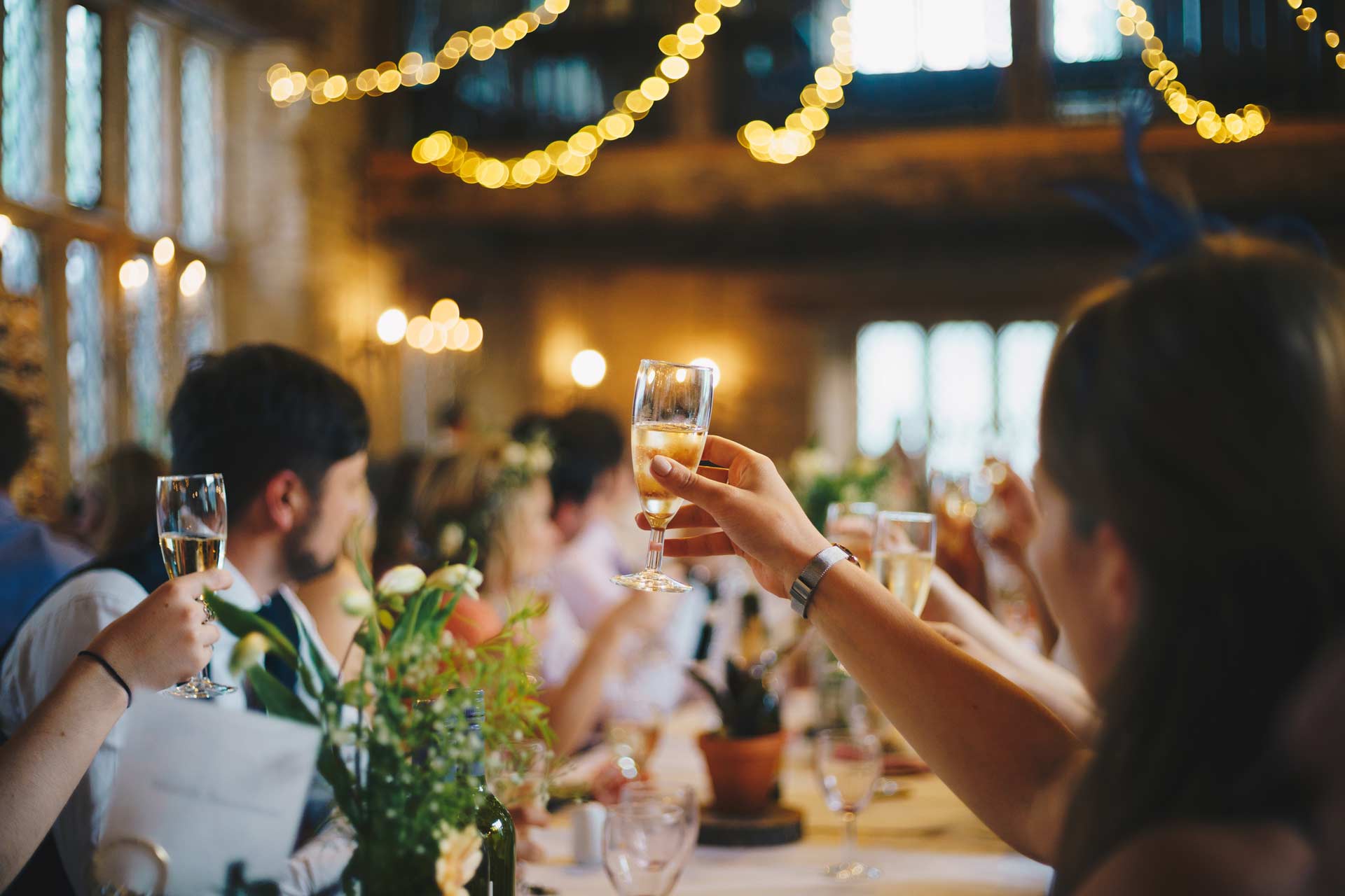 people sitting at a wedding table and holding champagne glasses aloft