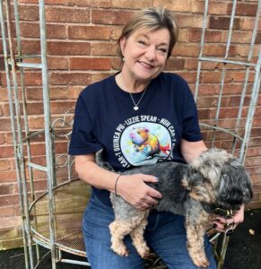 Lizzie Spear-sat outside with a small dog on her lap