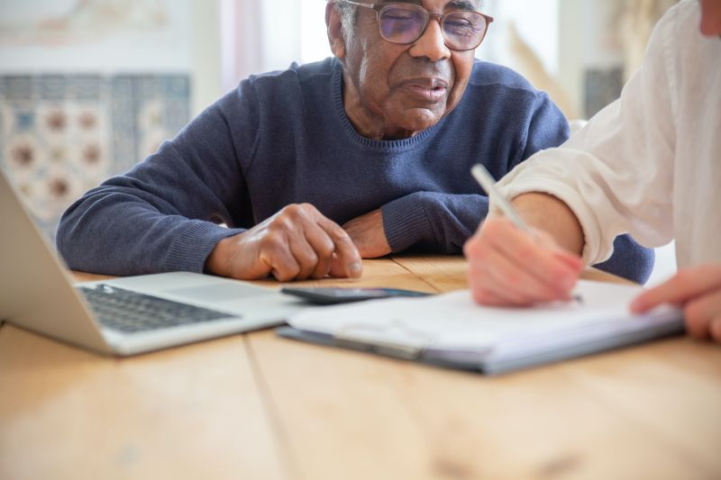Senior man receiving assistance with paperwork at home.
