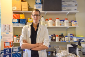 Prof. Simon Mitchell stood in a lab, white lab coat on, arms crossed